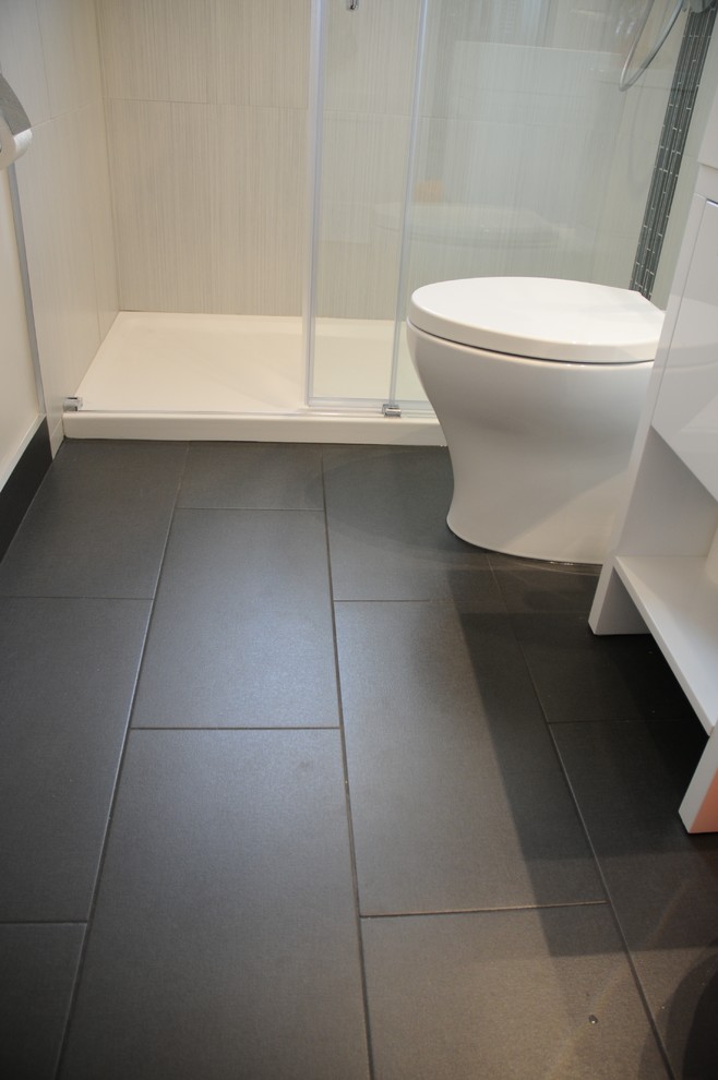 This is an example of a small modern bathroom in Toronto with white cabinets, an alcove shower, a two-piece toilet, black tiles, porcelain tiles and porcelain flooring.