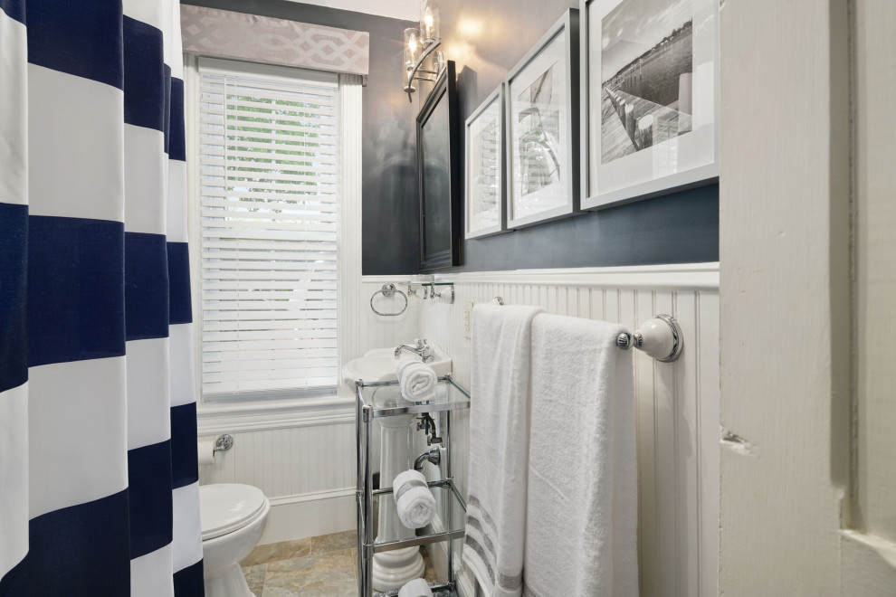 Bild på ett litet vintage badrum med dusch, med ett badkar med tassar, en dusch/badkar-kombination, en toalettstol med hel cisternkåpa, vit kakel, blå väggar, klinkergolv i keramik, ett avlångt handfat, beiget golv och dusch med duschdraperi
