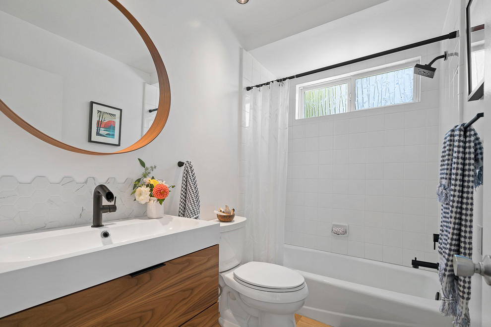 Inredning av ett klassiskt litet vit vitt badrum med dusch, med släta luckor, skåp i mellenmörkt trä, ett badkar i en alkov, en dusch/badkar-kombination, vit kakel, vita väggar, ljust trägolv, ett integrerad handfat, beiget golv och dusch med duschdraperi