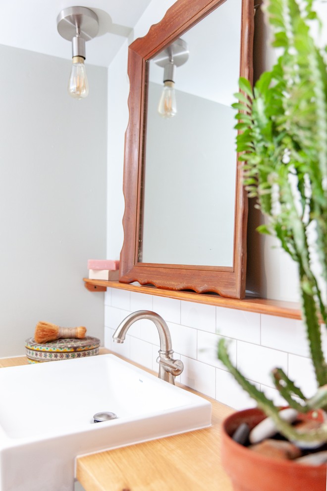 Inredning av ett lantligt litet brun brunt badrum, med en hörndusch, vit kakel, klinkergolv i porslin, träbänkskiva och grått golv