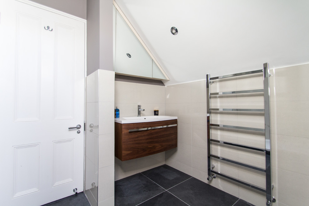 Inspiration for a small contemporary 3/4 ceramic tile doorless shower remodel in London with a drop-in sink, flat-panel cabinets, medium tone wood cabinets, a one-piece toilet and beige walls