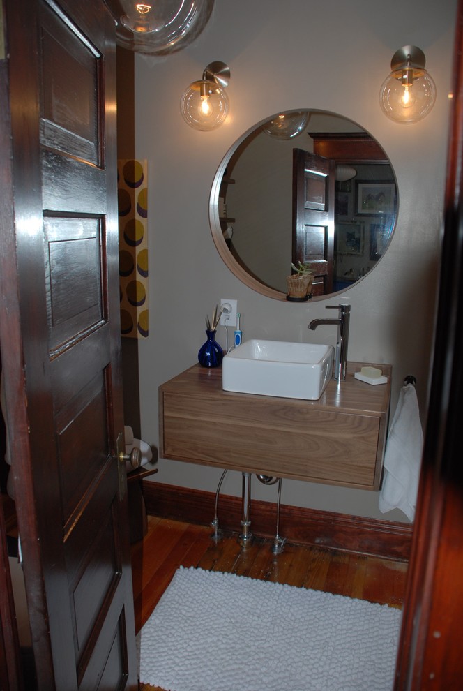This is an example of a small contemporary family bathroom in Denver with flat-panel cabinets, light wood cabinets, an alcove bath, a shower/bath combination, a one-piece toilet, grey walls, medium hardwood flooring, a vessel sink, wooden worktops, white tiles, porcelain tiles and a hinged door.