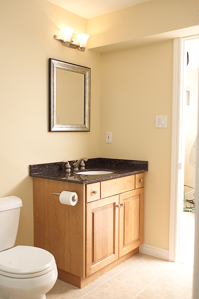 Cette image montre une salle de bain traditionnelle en bois clair avec un lavabo posé et un placard avec porte à panneau surélevé.