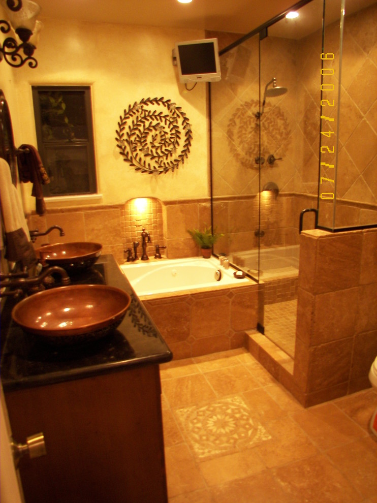 Aménagement d'une salle de bain méditerranéenne en bois foncé avec un placard en trompe-l'oeil, un bain bouillonnant, WC à poser, un sol en travertin, une vasque et un plan de toilette en granite.