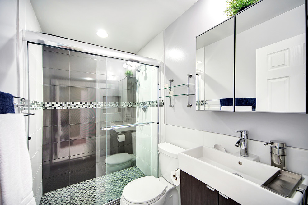 ワシントンD.C.にあるお手頃価格のコンテンポラリースタイルのおしゃれな浴室 (アルコーブ型シャワー、分離型トイレ、グレーのタイル、磁器タイル、一体型シンク、フラットパネル扉のキャビネット、濃色木目調キャビネット) の写真