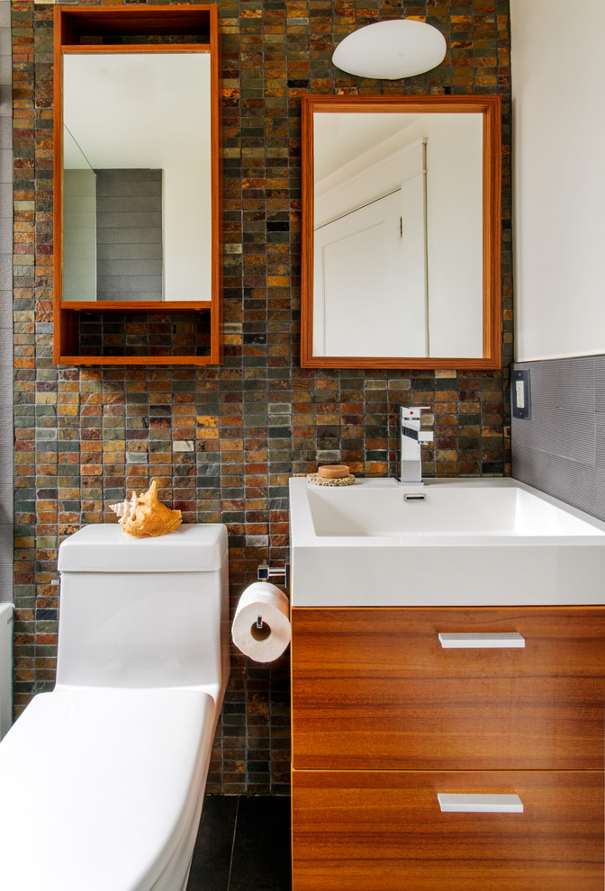 Cette photo montre une petite salle de bain tendance en bois brun pour enfant avec un lavabo intégré, un placard à porte plane, un plan de toilette en surface solide, WC à poser et du carrelage en ardoise.