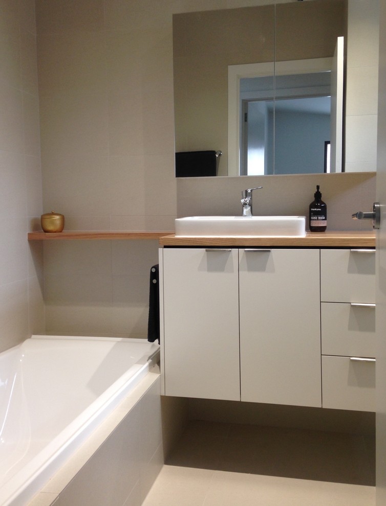 Inredning av ett modernt litet en-suite badrum, med möbel-liknande, vita skåp, ett platsbyggt badkar, en öppen dusch, beige kakel, porslinskakel, beige väggar, klinkergolv i porslin, ett nedsänkt handfat och träbänkskiva
