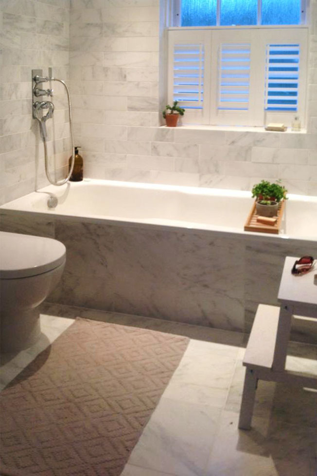 Small contemporary family bathroom in Berkshire with a console sink, white cabinets, marble worktops, a built-in bath, a shower/bath combination, a one-piece toilet, white tiles, stone tiles, white walls and marble flooring.
