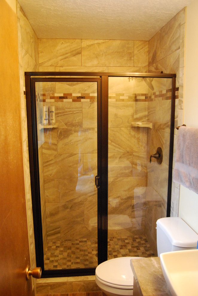 Photo of a small classic shower room bathroom in Other with a vessel sink, an alcove shower, a two-piece toilet, multi-coloured tiles, mosaic tiles, beige walls, recessed-panel cabinets, light wood cabinets, porcelain flooring, solid surface worktops, a hinged door and brown floors.