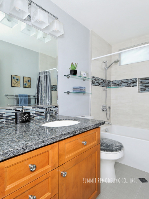 Small transitional 3/4 gray tile and glass tile porcelain tile bathroom photo in San Francisco with shaker cabinets, medium tone wood cabinets, a two-piece toilet, blue walls, an undermount sink and granite countertops