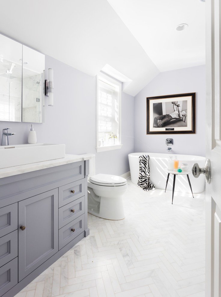 Exempel på ett mellanstort modernt en-suite badrum, med skåp i shakerstil, grå skåp, ett fristående badkar, en dusch i en alkov, en toalettstol med hel cisternkåpa, grå kakel, marmorkakel, lila väggar, marmorgolv, ett fristående handfat, marmorbänkskiva, grått golv och dusch med gångjärnsdörr