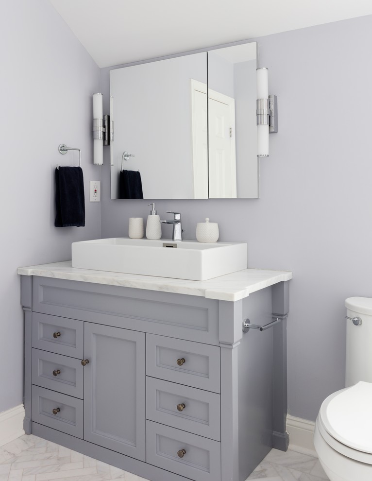 Medium sized contemporary grey and white ensuite bathroom in New York with shaker cabinets, grey cabinets, a freestanding bath, an alcove shower, a one-piece toilet, grey tiles, marble tiles, purple walls, marble flooring, a vessel sink, marble worktops, grey floors, a hinged door and a built in vanity unit.