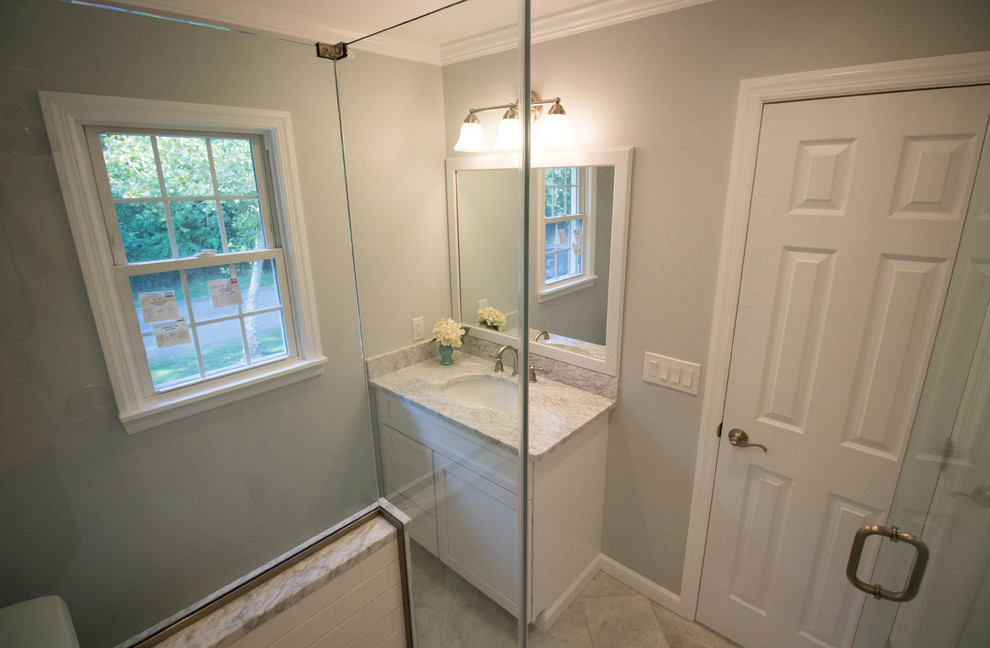 Small transitional master white tile and ceramic tile marble floor and gray floor corner shower photo in Newark with shaker cabinets, white cabinets, a two-piece toilet, gray walls, an undermount sink, marble countertops and a hinged shower door