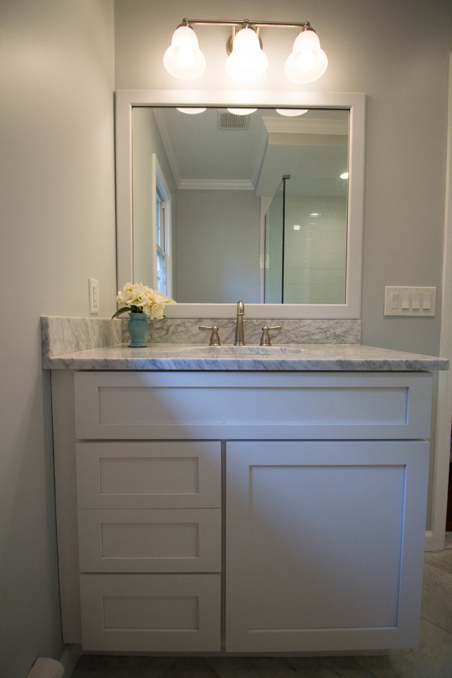 Small transitional master white tile and ceramic tile marble floor and gray floor corner shower photo in Newark with shaker cabinets, white cabinets, a two-piece toilet, gray walls, an undermount sink, marble countertops and a hinged shower door