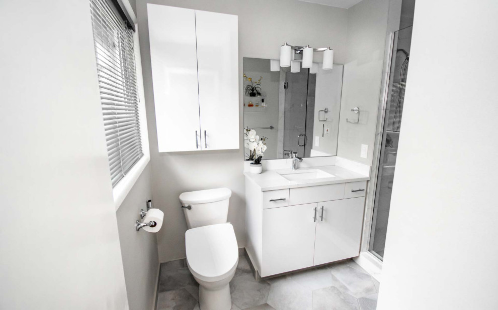 На фото: маленькая главная ванная комната в стиле неоклассика (современная классика) с плоскими фасадами, белыми фасадами, душем в нише, раздельным унитазом, белой плиткой, керамической плиткой, серыми стенами, полом из керамической плитки, врезной раковиной, столешницей из искусственного кварца, серым полом, душем с распашными дверями, белой столешницей, нишей, тумбой под одну раковину и встроенной тумбой для на участке и в саду с