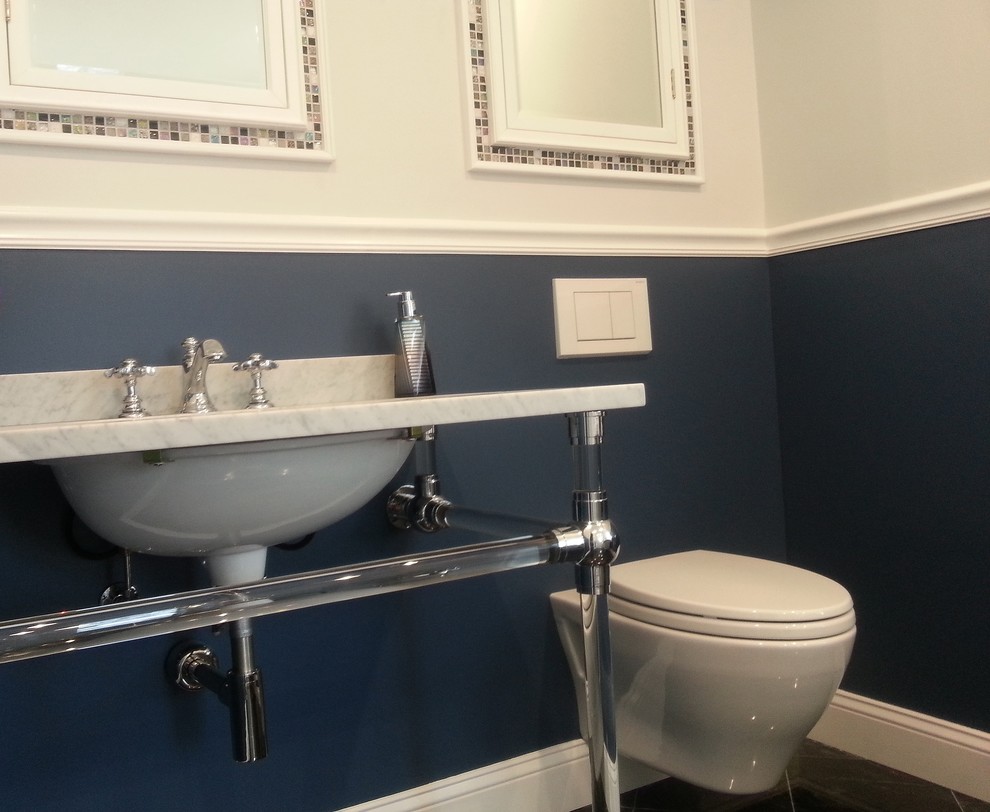 Foto de cuarto de baño principal clásico renovado de tamaño medio con lavabo tipo consola, encimera de mármol, bañera con patas, ducha empotrada, sanitario de pared, baldosas y/o azulejos grises, baldosas y/o azulejos en mosaico, paredes azules y suelo de mármol