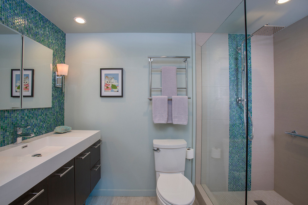 Cette image montre une salle de bain principale traditionnelle en bois foncé de taille moyenne avec un placard à porte plane, une douche ouverte, WC à poser, un carrelage beige, mosaïque, un mur bleu, un lavabo intégré et un sol en carrelage de porcelaine.