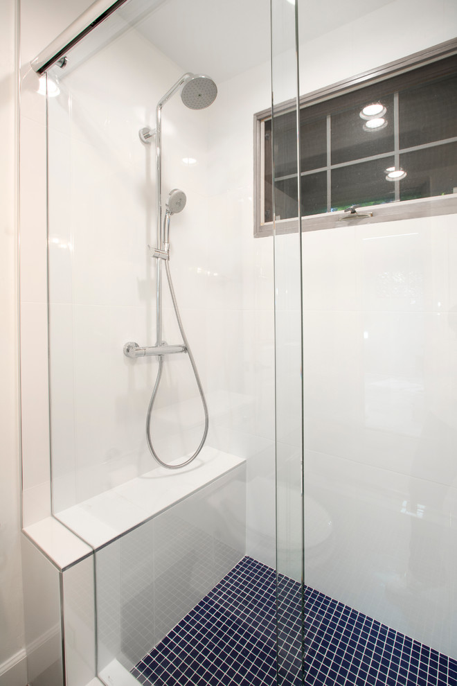 Modern inredning av ett litet badrum, med luckor med glaspanel, vita skåp, en öppen dusch, en toalettstol med separat cisternkåpa, vit kakel, porslinskakel, vita väggar, klinkergolv i porslin, ett integrerad handfat och bänkskiva i onyx