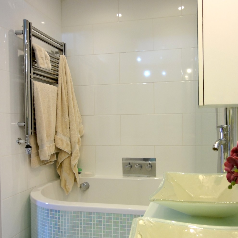 Idées déco pour une petite salle de bain moderne avec une vasque, des portes de placard blanches, un plan de toilette en verre, une baignoire en alcôve, un combiné douche/baignoire, un carrelage blanc, des carreaux de céramique et un mur blanc.