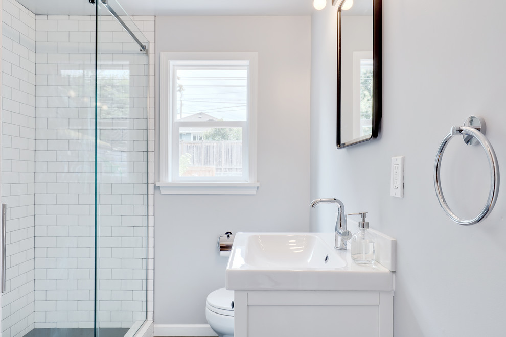 Cette image montre une petite salle d'eau minimaliste avec un placard à porte plane, des portes de placard blanches, une douche ouverte, un carrelage blanc, un carrelage métro et un plan de toilette blanc.
