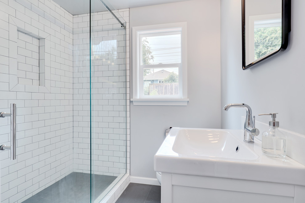 Inredning av ett modernt litet vit vitt badrum med dusch, med släta luckor, vita skåp, en öppen dusch, en toalettstol med hel cisternkåpa, vit kakel, tunnelbanekakel, grå väggar, klinkergolv i porslin, ett integrerad handfat och grått golv