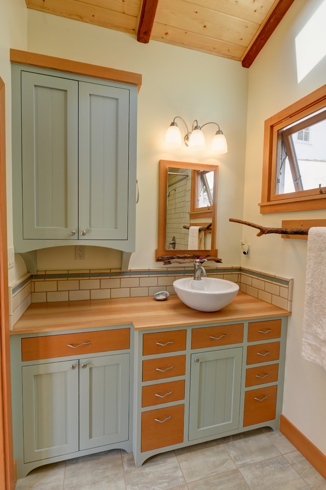 Small nautical shower room bathroom in San Diego with flat-panel cabinets, green cabinets, a corner shower, beige tiles, ceramic tiles, yellow walls, porcelain flooring, a vessel sink, wooden worktops and a shower curtain.