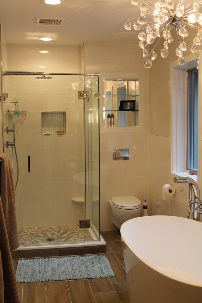 Bild på ett mellanstort funkis en-suite badrum, med ett fristående handfat, släta luckor, vita skåp, bänkskiva i kvarts, ett fristående badkar, en hörndusch, en vägghängd toalettstol, vit kakel, porslinskakel, vita väggar och klinkergolv i porslin
