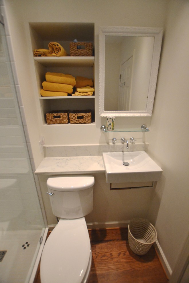 На фото: главная ванная комната с раздельным унитазом, белой плиткой, керамогранитной плиткой, белыми стенами, темным паркетным полом, подвесной раковиной, мраморной столешницей, коричневым полом и душем с распашными дверями