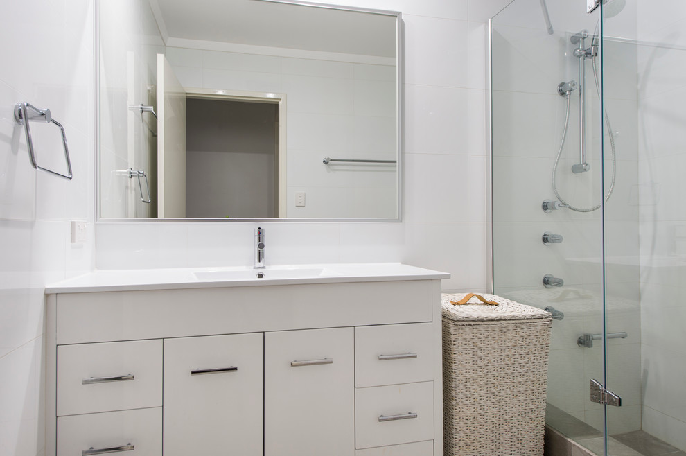 Inspiration för ett litet funkis badrum med dusch, med släta luckor, vita skåp, bänkskiva i akrylsten, en dusch/badkar-kombination, vit kakel, keramikplattor, vita väggar och klinkergolv i keramik