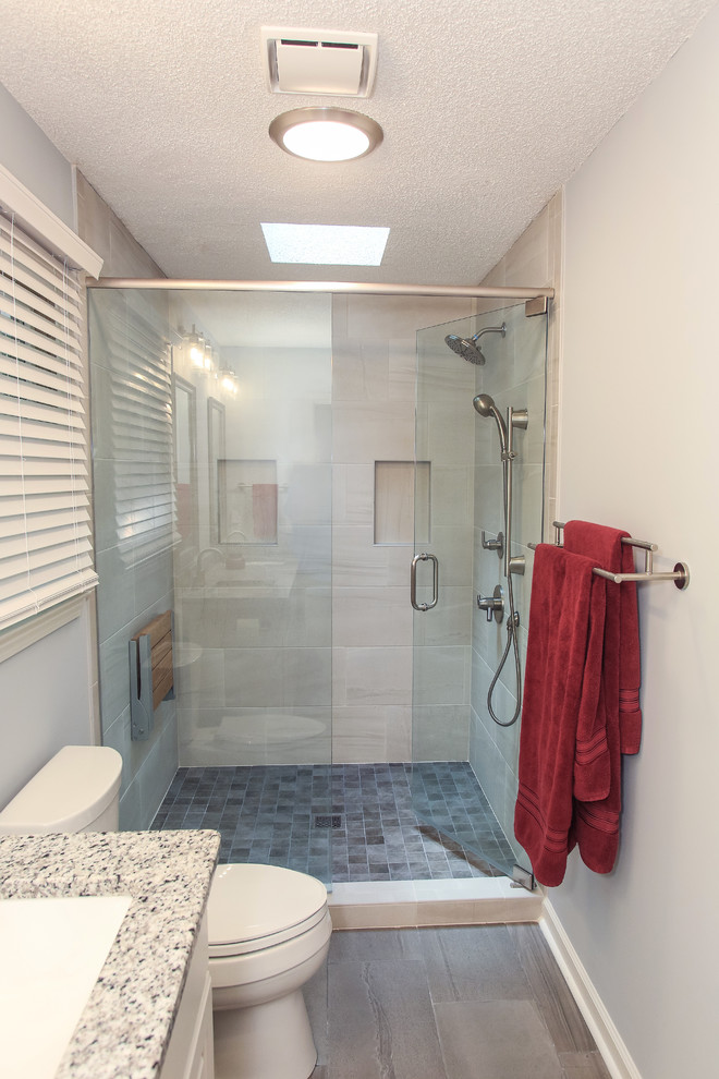Medium sized traditional shower room bathroom in Atlanta with raised-panel cabinets, white cabinets, an alcove shower, a two-piece toilet, beige tiles, porcelain tiles, blue walls, porcelain flooring, a submerged sink, granite worktops, grey floors, a hinged door and multi-coloured worktops.