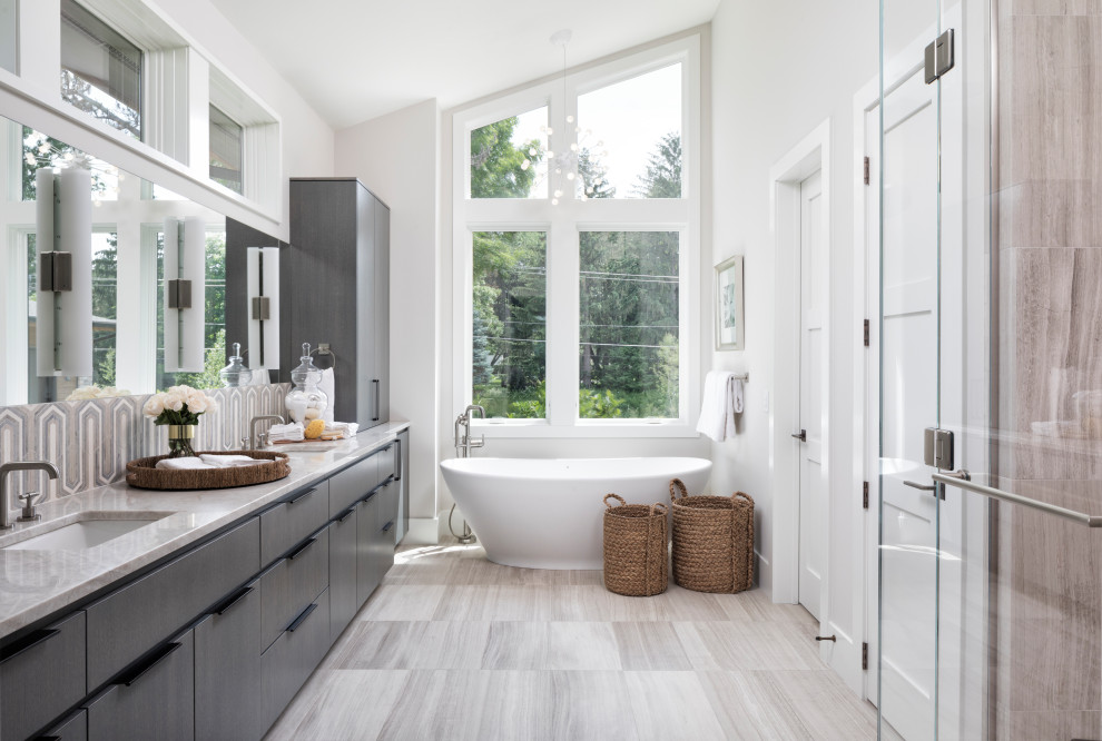 Inspiration för stora moderna grått en-suite badrum, med släta luckor, grå skåp, ett fristående badkar, grå väggar, ett undermonterad handfat, grått golv och klinkergolv i porslin