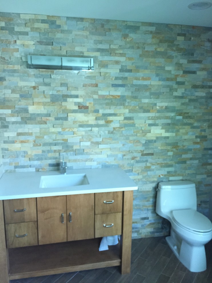 Foto di una stanza da bagno con doccia american style di medie dimensioni con lavabo integrato, ante lisce, ante in legno scuro, WC monopezzo, piastrelle marroni e piastrelle in pietra
