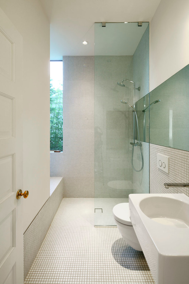 Diseño de cuarto de baño contemporáneo con lavabo suspendido, ducha abierta, sanitario de pared, baldosas y/o azulejos blancos, baldosas y/o azulejos en mosaico, paredes blancas, suelo con mosaicos de baldosas y ducha abierta