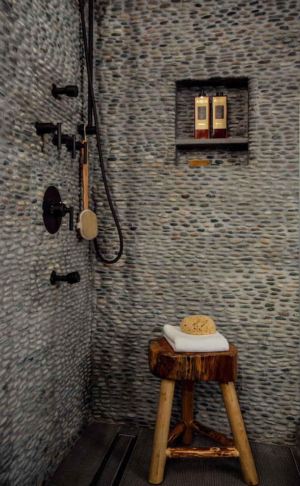 Aménagement d'une salle de bain montagne avec un carrelage gris et une plaque de galets.