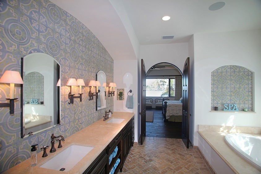 Пример оригинального дизайна: большая главная ванная комната в средиземноморском стиле с врезной раковиной, фасадами островного типа, темными деревянными фасадами, мраморной столешницей, накладной ванной, синей плиткой, цементной плиткой, белыми стенами и кирпичным полом