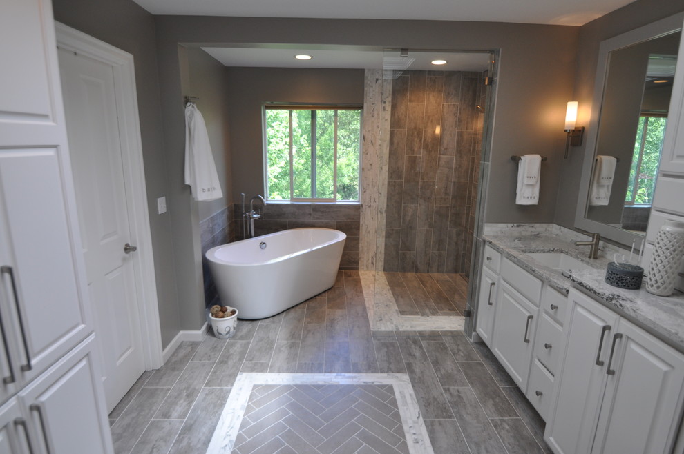 Photo of a large modern ensuite bathroom in Seattle with a submerged sink, raised-panel cabinets, white cabinets, engineered stone worktops, a freestanding bath, a built-in shower, grey tiles, porcelain tiles, grey walls and porcelain flooring.