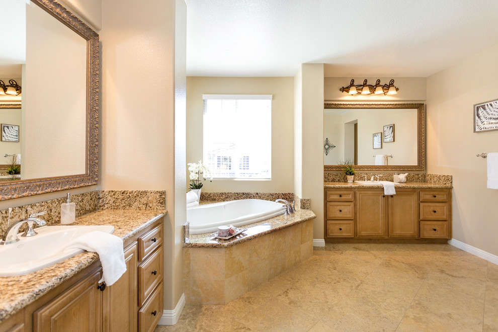 Klassisk inredning av ett stort en-suite badrum, med luckor med infälld panel, skåp i mellenmörkt trä, ett platsbyggt badkar, beige väggar, klinkergolv i keramik, ett nedsänkt handfat och granitbänkskiva