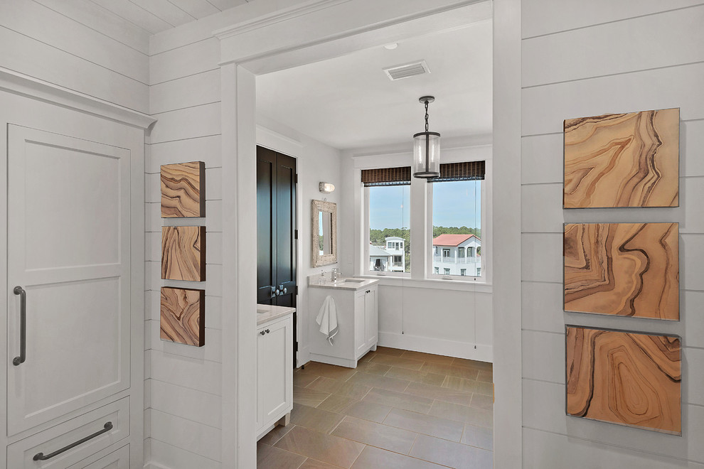 マイアミにあるビーチスタイルのおしゃれな浴室 (シェーカースタイル扉のキャビネット、白いキャビネット、白い壁、磁器タイルの床、壁付け型シンク) の写真