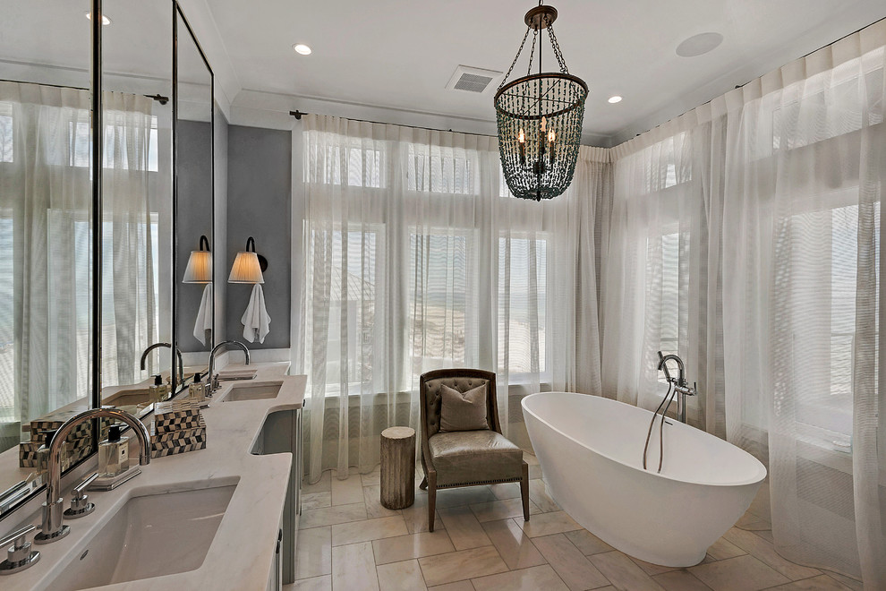 Photo of a large beach style bathroom in Miami with a freestanding bath, a submerged sink, shaker cabinets, grey cabinets, porcelain flooring, marble worktops and feature lighting.