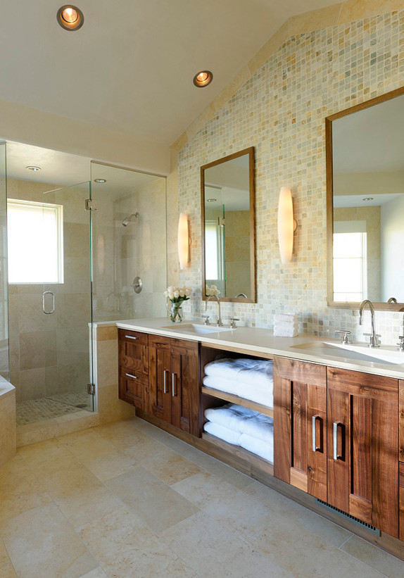 This is an example of a large traditional ensuite bathroom in Denver with shaker cabinets, medium wood cabinets, a submerged bath, a two-piece toilet, multi-coloured tiles, stone tiles, beige walls, limestone flooring, a submerged sink and solid surface worktops.