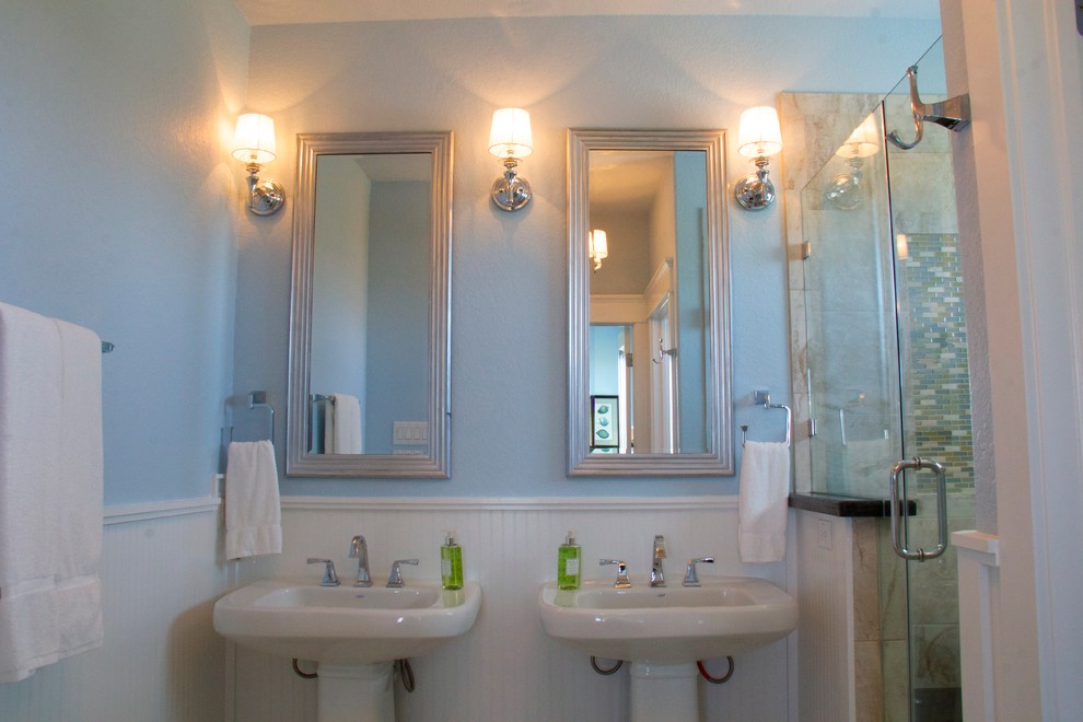 Immagine di una stanza da bagno con doccia stile marino di medie dimensioni con lavabo a colonna, doccia alcova, piastrelle beige, piastrelle in gres porcellanato, pareti blu e pavimento in travertino