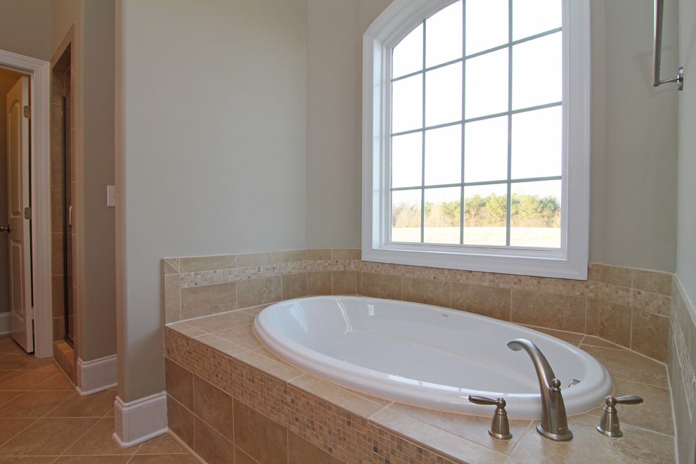 Modelo de cuarto de baño principal rústico de tamaño medio con bañera esquinera, ducha esquinera, sanitario de una pieza, paredes beige y suelo de baldosas de cerámica