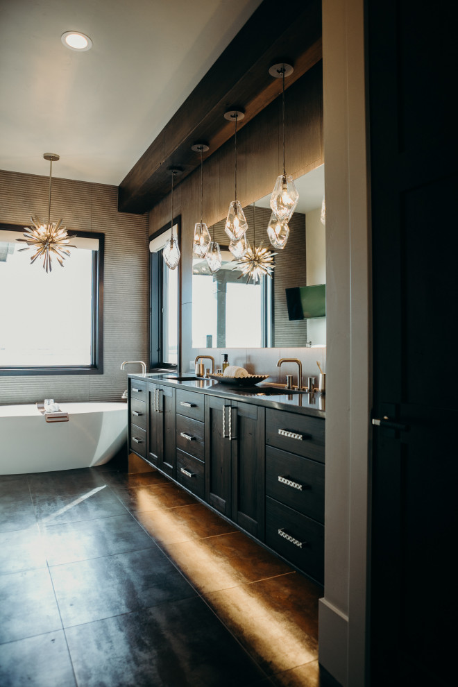 Inspiration for a rustic bathroom in Denver with shaker cabinets, dark wood cabinets, a freestanding bath, grey tiles, a submerged sink, black floors, black worktops, double sinks and a built in vanity unit.