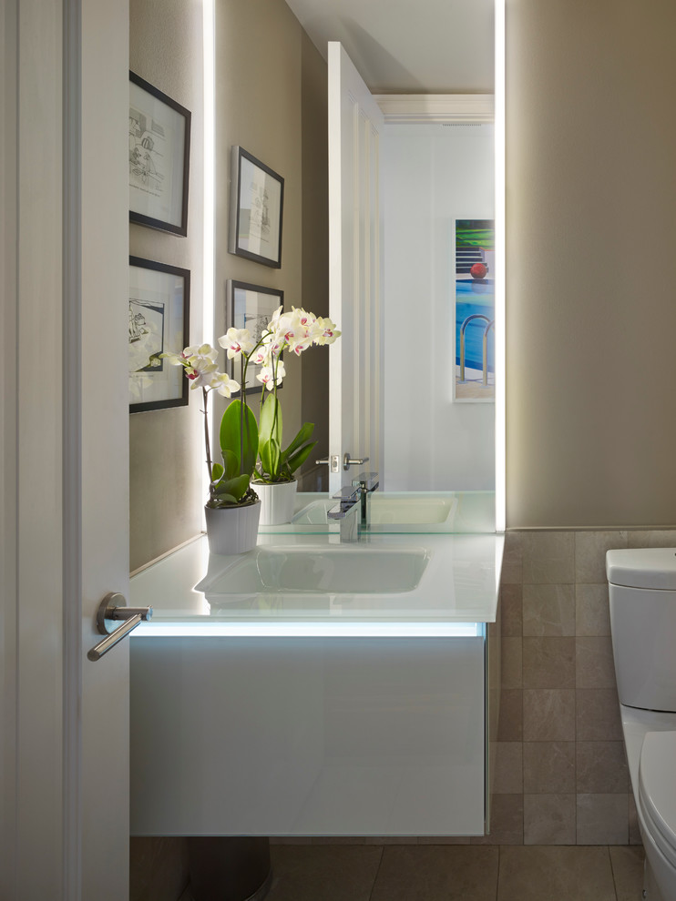 Ispirazione per una grande stanza da bagno minimal con lavabo integrato, ante lisce, top in vetro, WC a due pezzi e pareti beige