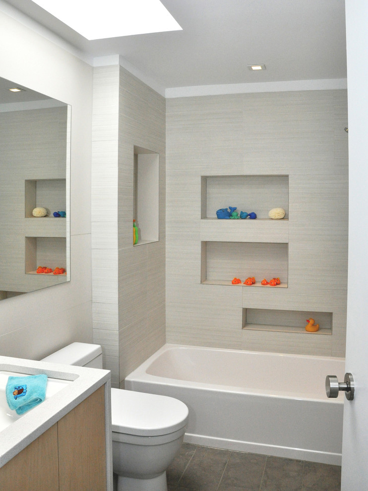 Стильный дизайн: детская ванная комната в современном стиле с врезной раковиной, плоскими фасадами, светлыми деревянными фасадами, столешницей из искусственного кварца, ванной в нише, душем в нише, унитазом-моноблоком, серой плиткой, керамогранитной плиткой и полом из керамогранита - последний тренд