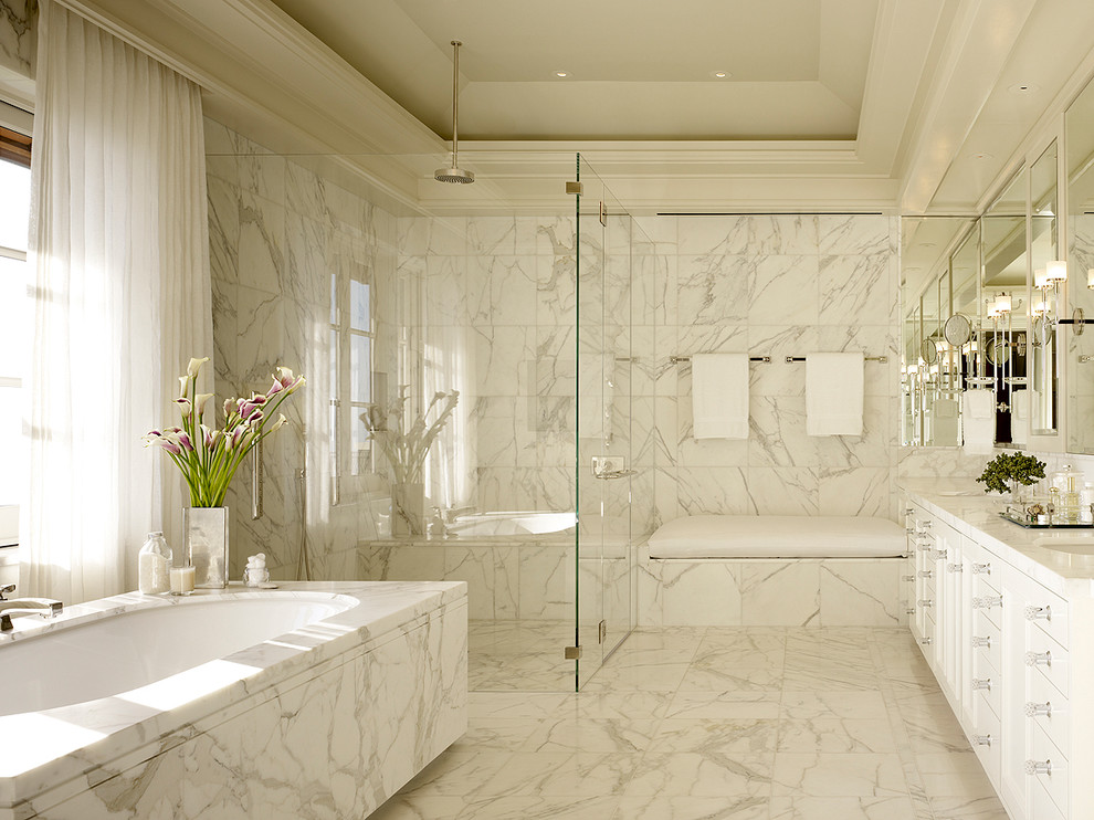 На фото: ванная комната в классическом стиле с врезной раковиной, белыми фасадами, полновстраиваемой ванной, угловым душем, белой плиткой и мраморной плиткой