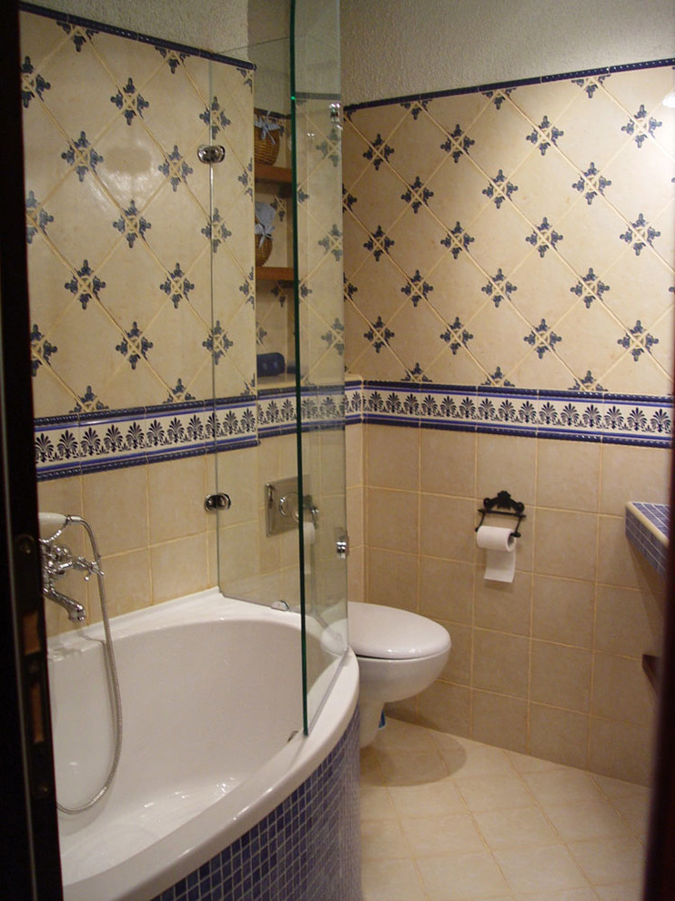 Foto di una piccola stanza da bagno mediterranea con vasca ad angolo, doccia alcova, WC monopezzo, piastrelle beige, piastrelle in ceramica, pareti beige, pavimento con piastrelle in ceramica, lavabo integrato e top piastrellato