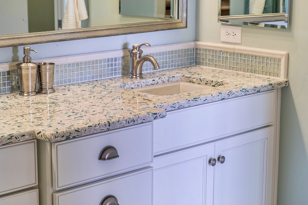 Beach style beige tile bathroom photo in San Diego with a vessel sink, flat-panel cabinets, white cabinets and limestone countertops