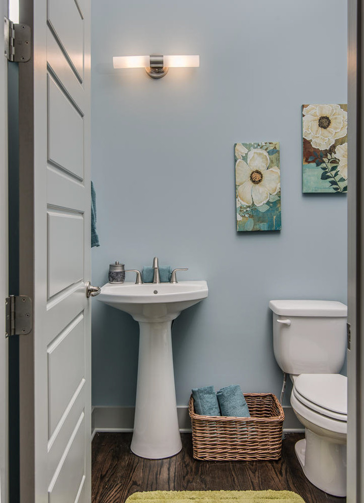 Modelo de cuarto de baño actual pequeño con sanitario de una pieza, paredes azules, suelo de madera oscura, aseo y ducha y lavabo con pedestal
