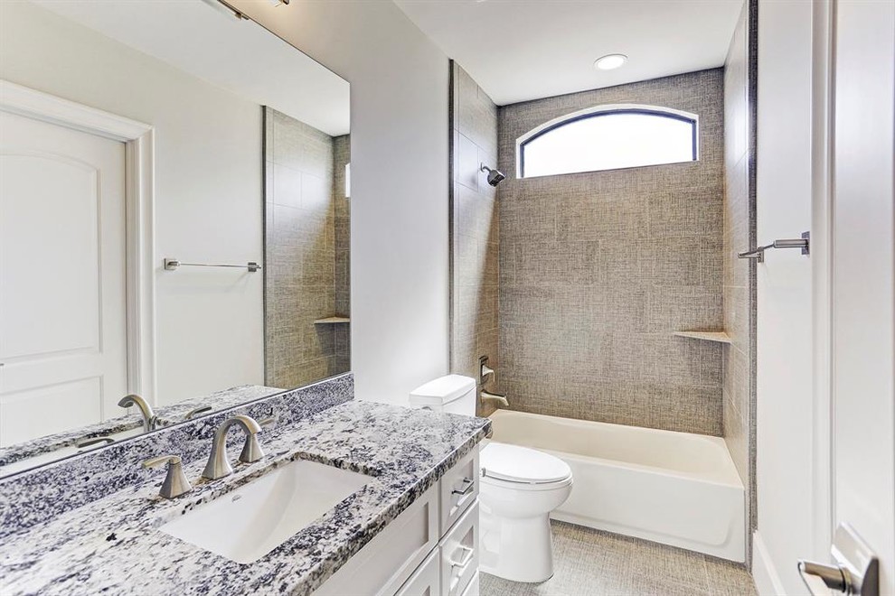 Пример оригинального дизайна: большая ванная комната в современном стиле с фасадами в стиле шейкер, белыми фасадами, ванной в нише, душем над ванной, раздельным унитазом, серой плиткой, плиткой из листового камня, серыми стенами, полом из керамической плитки, врезной раковиной, мраморной столешницей, серым полом, шторкой для ванной и белой столешницей